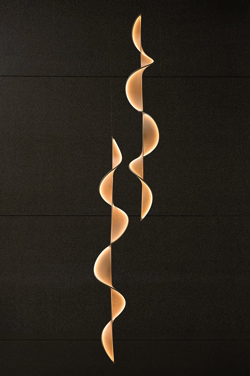 A 360 cm double llll.08 sculptural pendant light shown from an angled perspective, highlighting the mirrored connection between the two llll.08 modules. The flowing wave geometry appears more dimensional from this viewpoint, revealing the layered curvature and warm downward glow. The elongated 3.6‑meter span creates a striking architectural line, ideal for large contemporary interiors seeking a refined, atmospheric lighting statement.